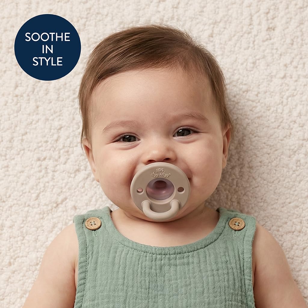 Older infant with the taupe Itzy Ritzy shield, listing badge reading soothe in style
